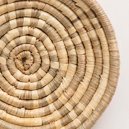 Closeup of handwoven wall basket showing tightly coiled natural fiber texture highlighting artisan craftsmanship and decor detailing.