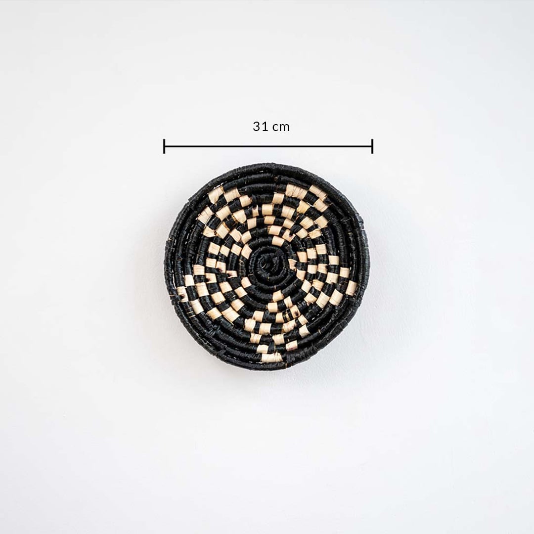 Handwoven round wall basket in black and natural fiber showing approx 25 cm diameter for accurate wall decor placement reference.