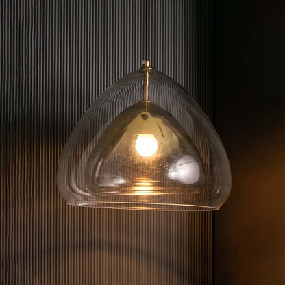 Golden glass pendant light turned on against a dark black background creating a striking warm illumination that highlights the curved glass design.
