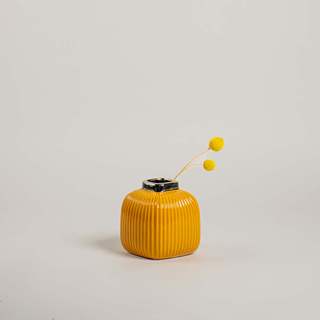 Modern yellow ceramic vase with ribbed texture displayed on a simple white background highlighting its bright finish.