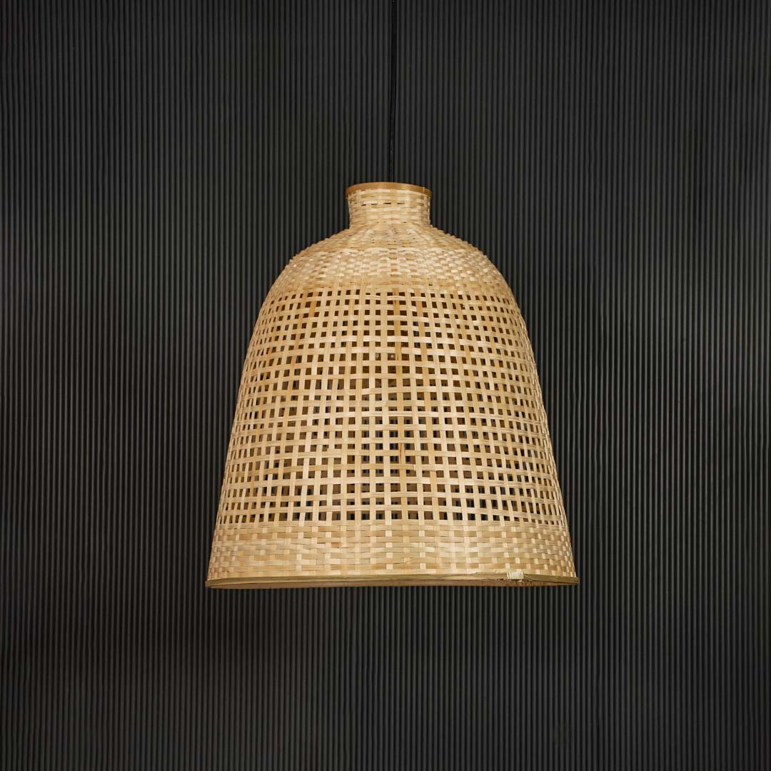 Rattan pendant light with tall handwoven bamboo shade in natural finish turned off against black background.