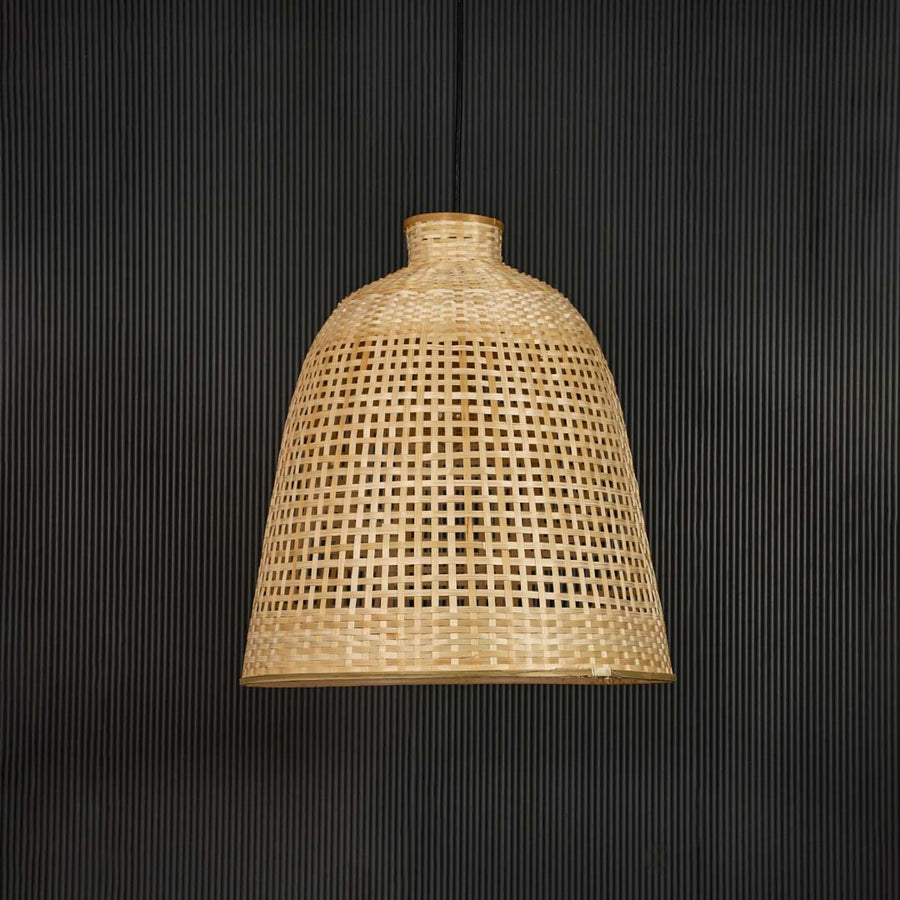 Rattan pendant light with tall handwoven bamboo shade in natural finish turned off against black background.
