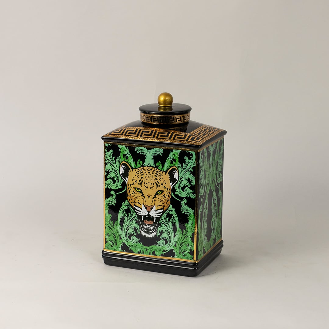 Side angle view of black ceramic jar showing elegant golden top and bold leopard-themed artwork.
