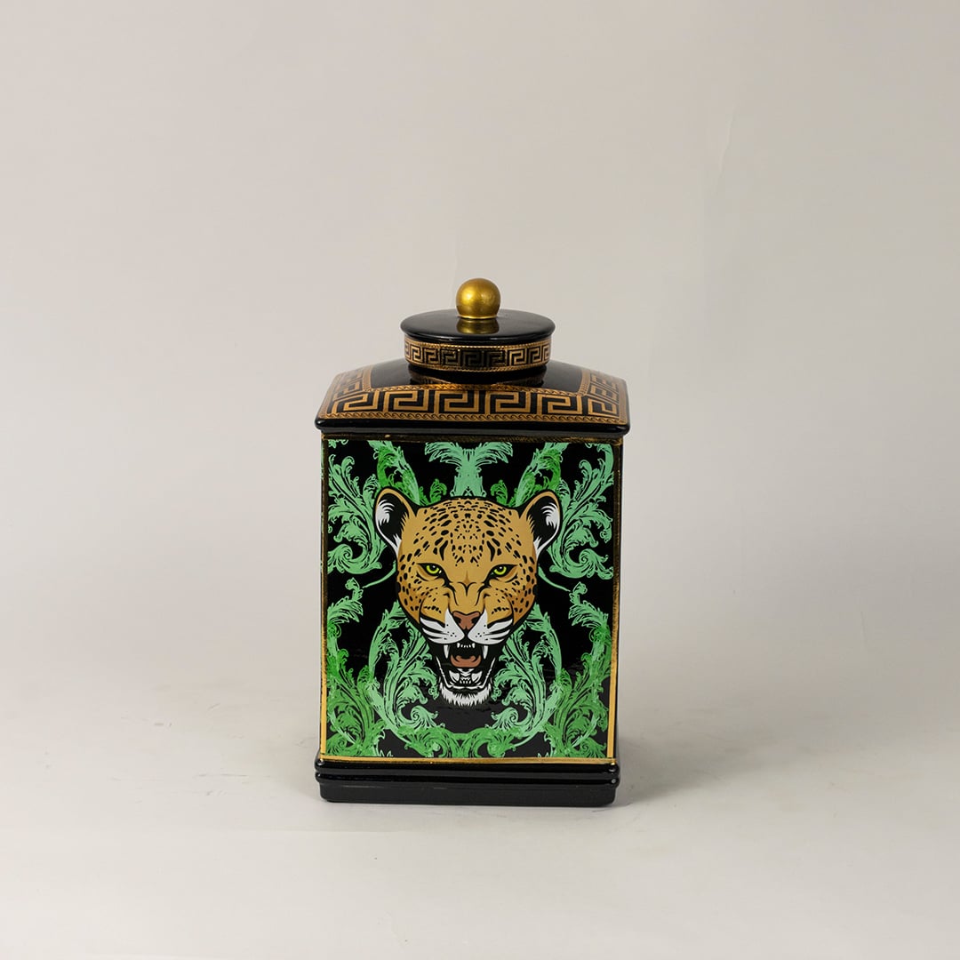 Black ceramic jar against white backdrop emphasizing glossy finish and vivid gold-green detailing.