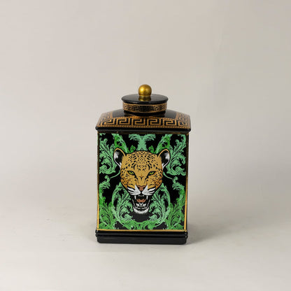 Black ceramic jar against white backdrop emphasizing glossy finish and vivid gold-green detailing.