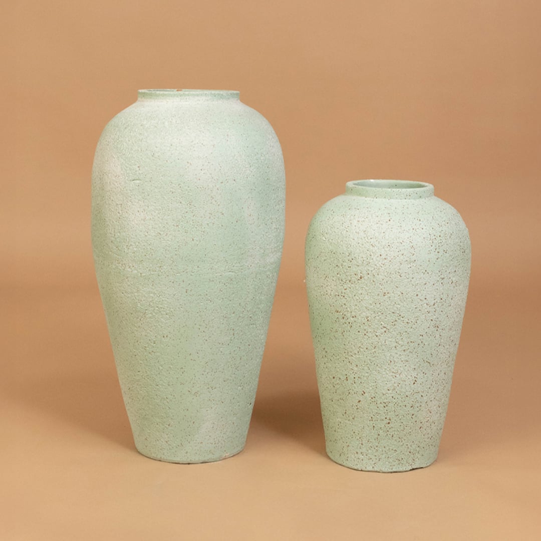 Grouped display of mint green ceramic vase styled with decor pieces creating a modern elegant look for living room or hallway spaces.