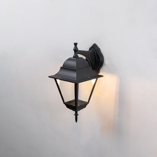Black metal outdoor wall light on white background with clear glass shade for classic patio lighting decor.
