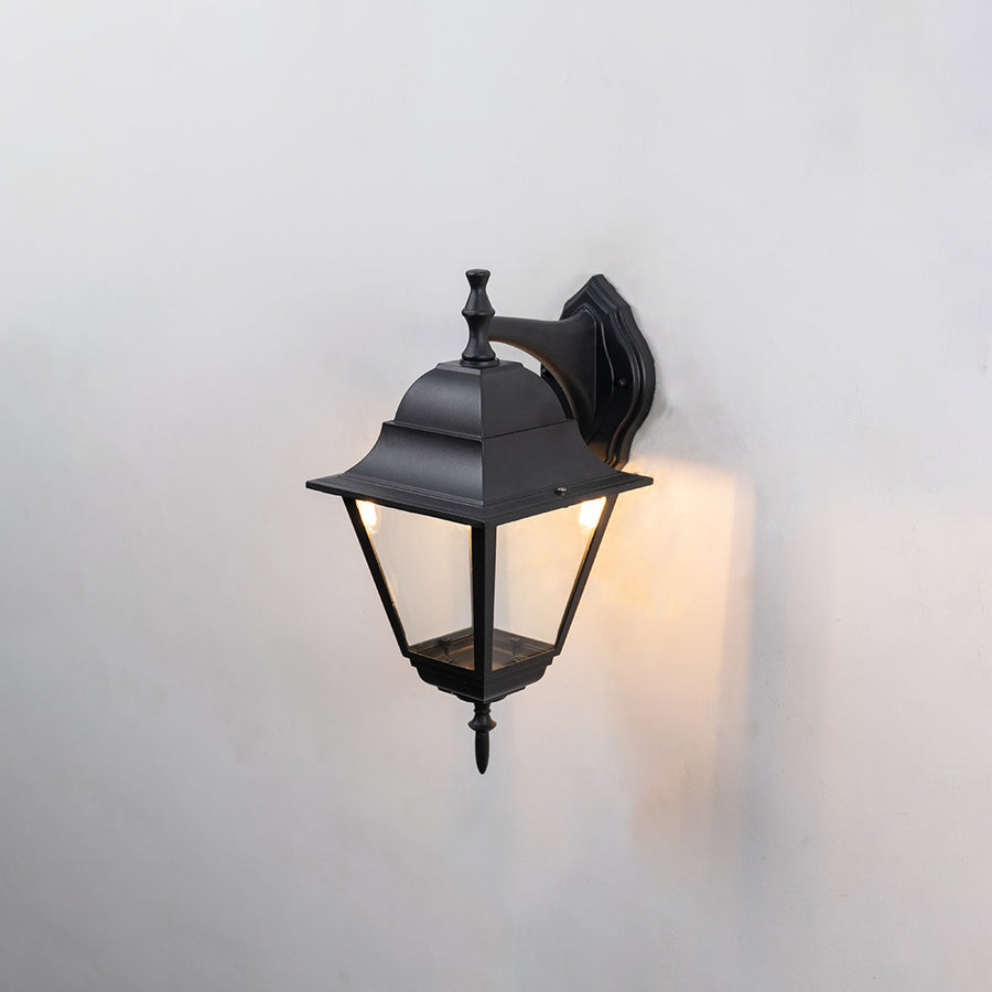 Black metal outdoor wall light on white background with clear glass shade for classic patio lighting decor.