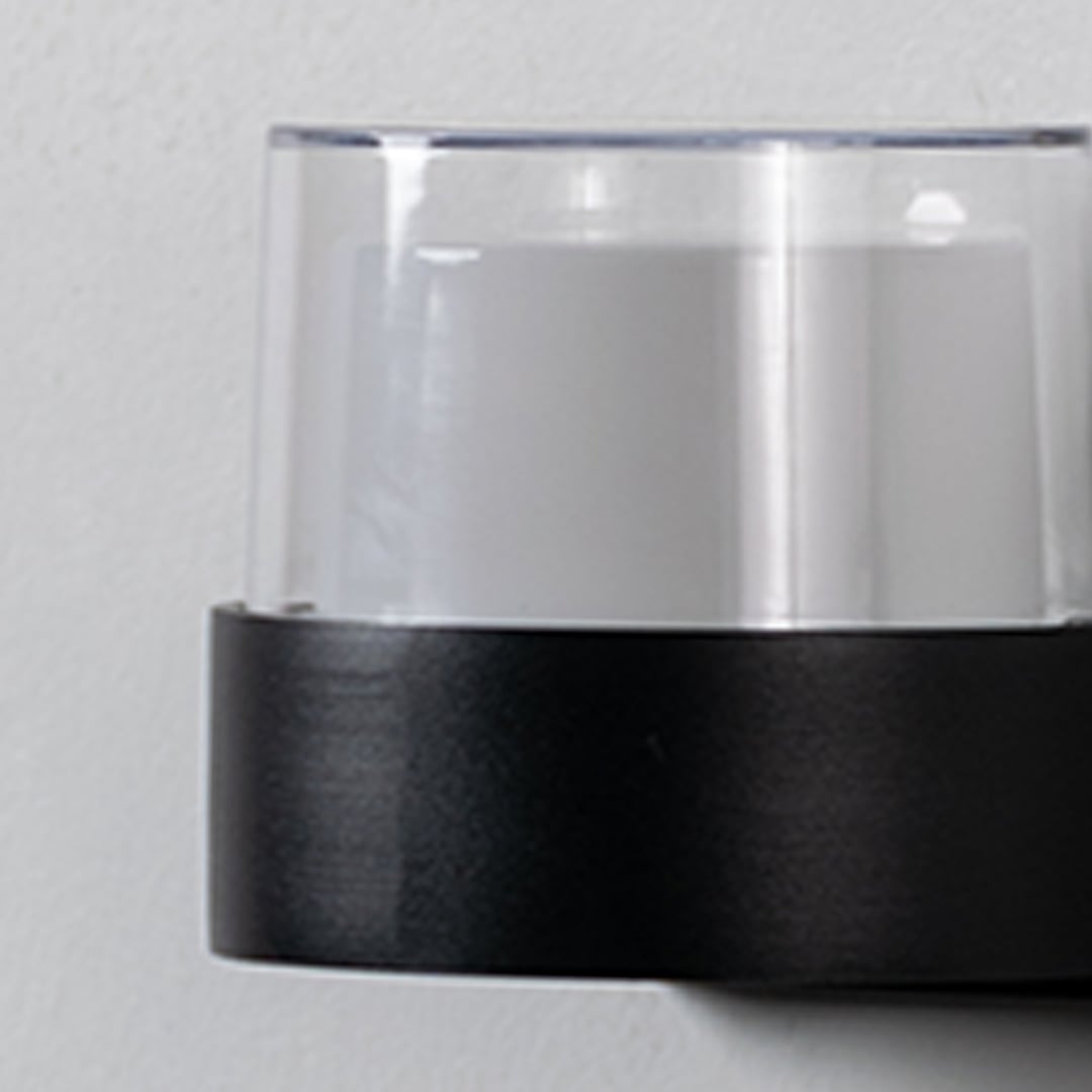Closeup of modern wall light highlighting matte black base with clear glass shade designed for stylish and balanced lighting.