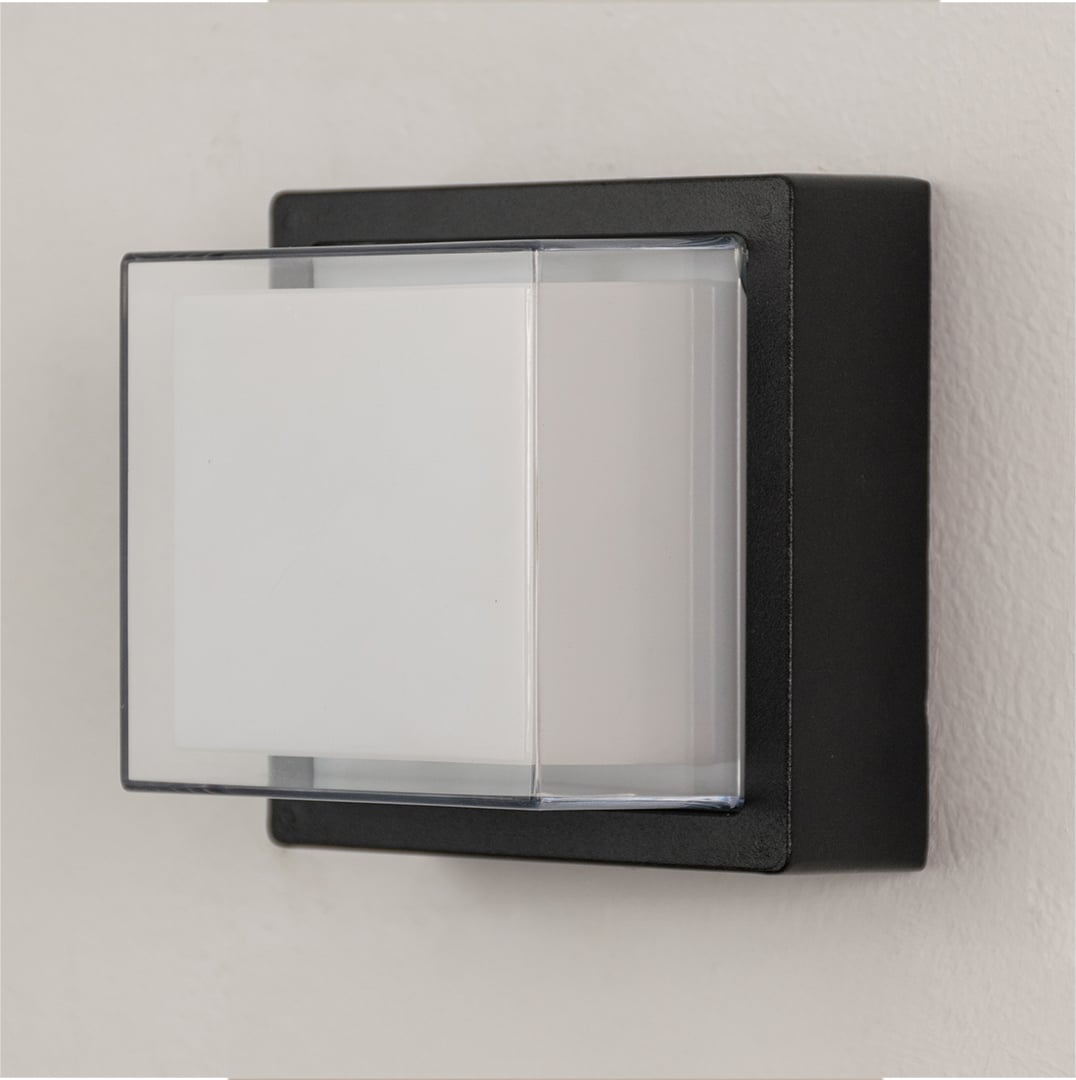 Black metal wall light on white background with frosted glass shade for modern minimalist exterior decor.