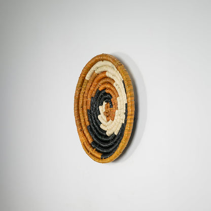 Round jute and black woven wall basket decor handmade rustic boho spiral design wall art accent piece shown from side view.