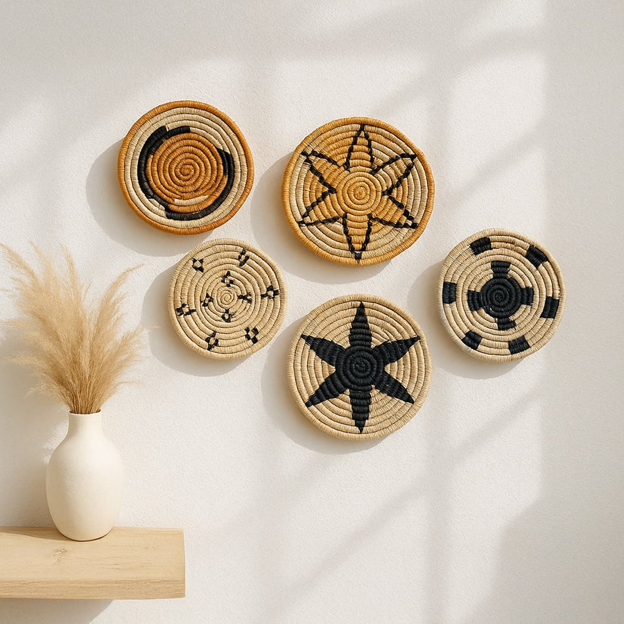 Set of handwoven jute wall basket decor in beige black and brown star and spiral designs styled on white wall for boho living room.