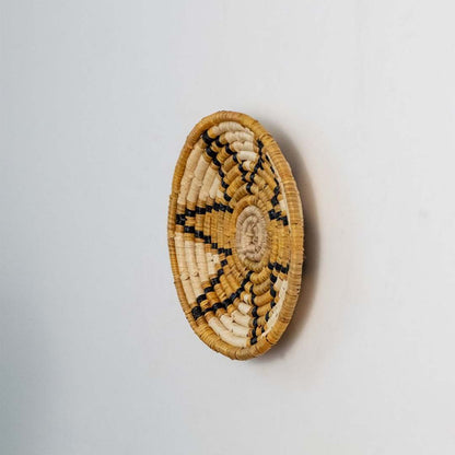 Round jute and black woven wall basket decor handmade rustic boho star design wall art accent piece shown side angle view.