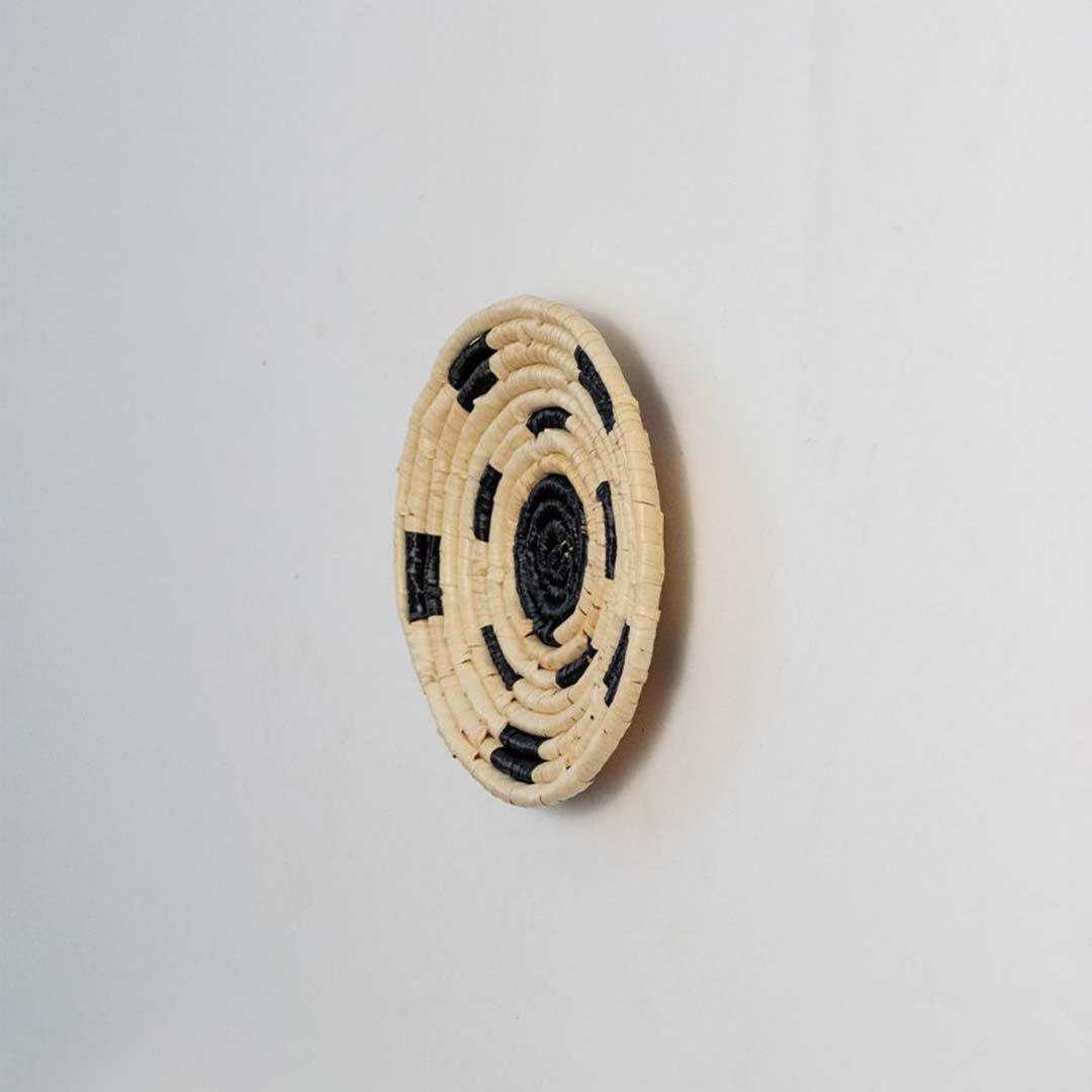 Side view of woven basket showing shallow depth and raised coil edge illustrating how the handwoven disc sits slightly off the wall when hung.