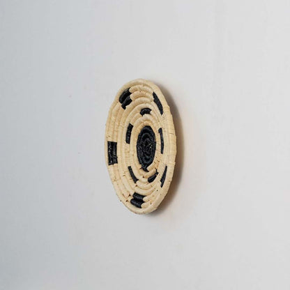Side view of woven basket showing shallow depth and raised coil edge illustrating how the handwoven disc sits slightly off the wall when hung.