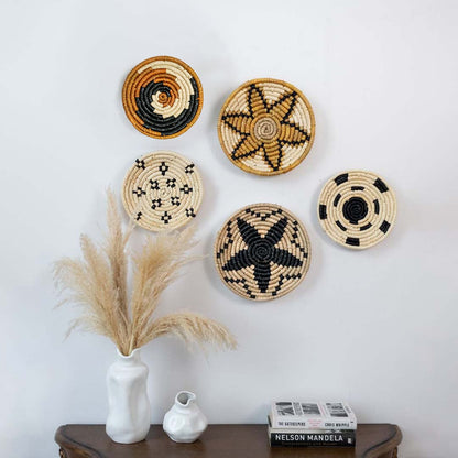 Set of handwoven jute wall basket decor in beige black and brown rustic boho spiral and star designs styled on white wall.