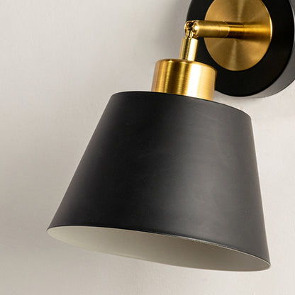 Closeup of black and gold metal wall light with cone shade for elegant bedroom hallway and living room decor.
