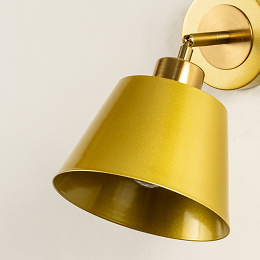Closeup of gold metal wall light with cone shade showcasing smooth finish and premium detailing for modern interior decor styling.