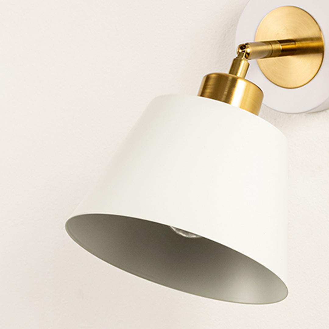 Wall light with white cone shade casting soft glow styled in home interior creating warm ambient lighting for wall decor.