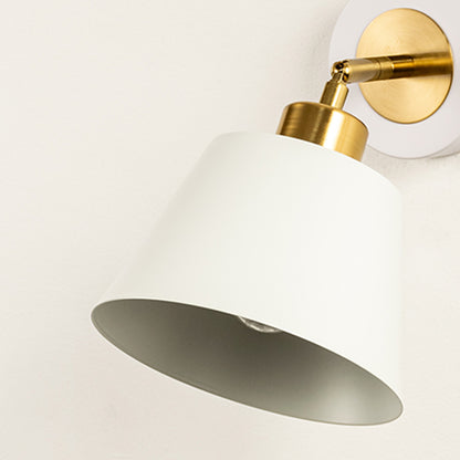 Wall light with white cone shade casting soft glow styled in home interior creating warm ambient lighting for wall decor.