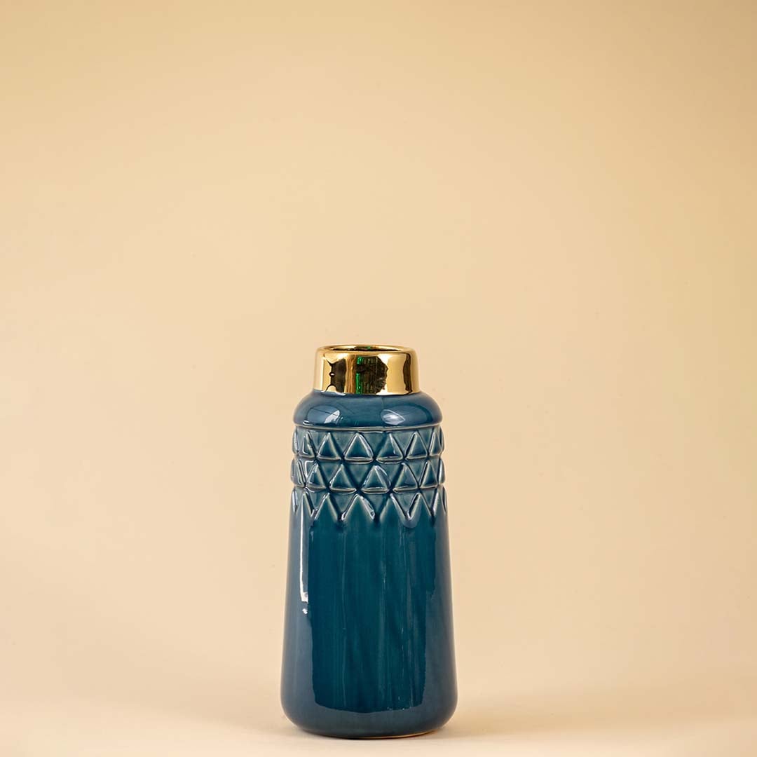 A tall blue ceramic vase with a glossy finish and gold rim photographed on a white background highlighting its smooth textured surface and modern decorative shape.