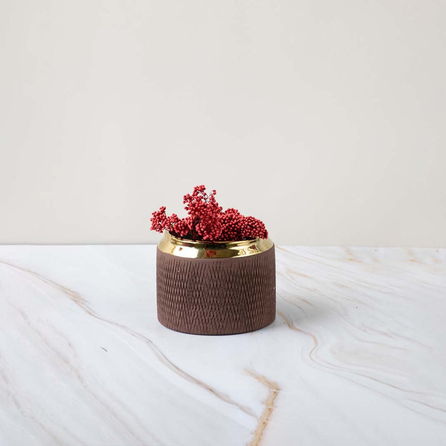 A low brown vase with a gold rim placed on a soft marble background showing a refined stylish look perfect for enhancing modern interiors.