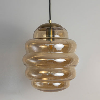 Amber ripple pendant lights softly illuminated sgainst white background adding elegant warm lighting to contemporary home interiors.
