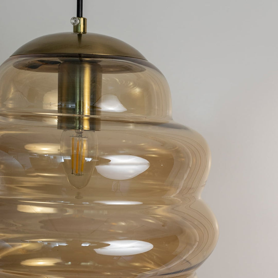 Closeup of amber ripple pendant light showing layered glass pattern with rich amber tint and polished finish.