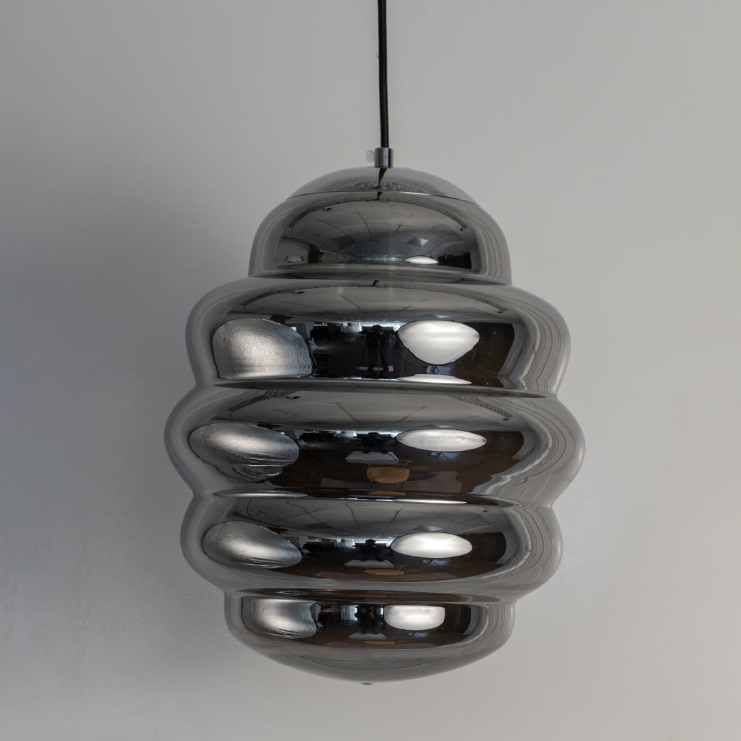 Macro shot of chrome ripple pendant light focusing on the smooth reflective layers that create its distinctive rippled pattern.