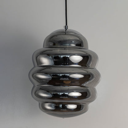 Macro shot of chrome ripple pendant light focusing on the smooth reflective layers that create its distinctive rippled pattern.