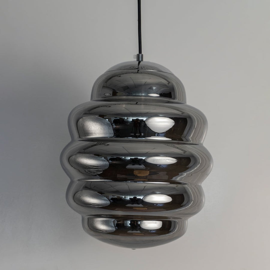 Macro shot of chrome ripple pendant light focusing on the smooth reflective layers that create its distinctive rippled pattern.