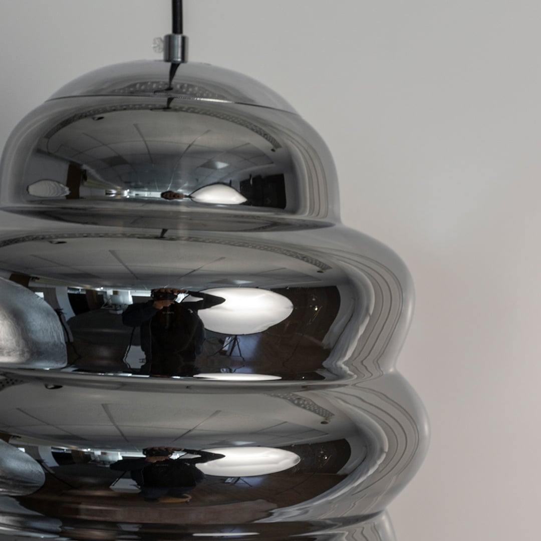 Closeup of ripple chrome pendant light highlighting smooth metallic ripples and high-gloss reflective finish.