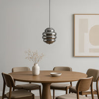 Chrome layered glass pendant light suspended above dining table adding modern elegance and warm ambiance.