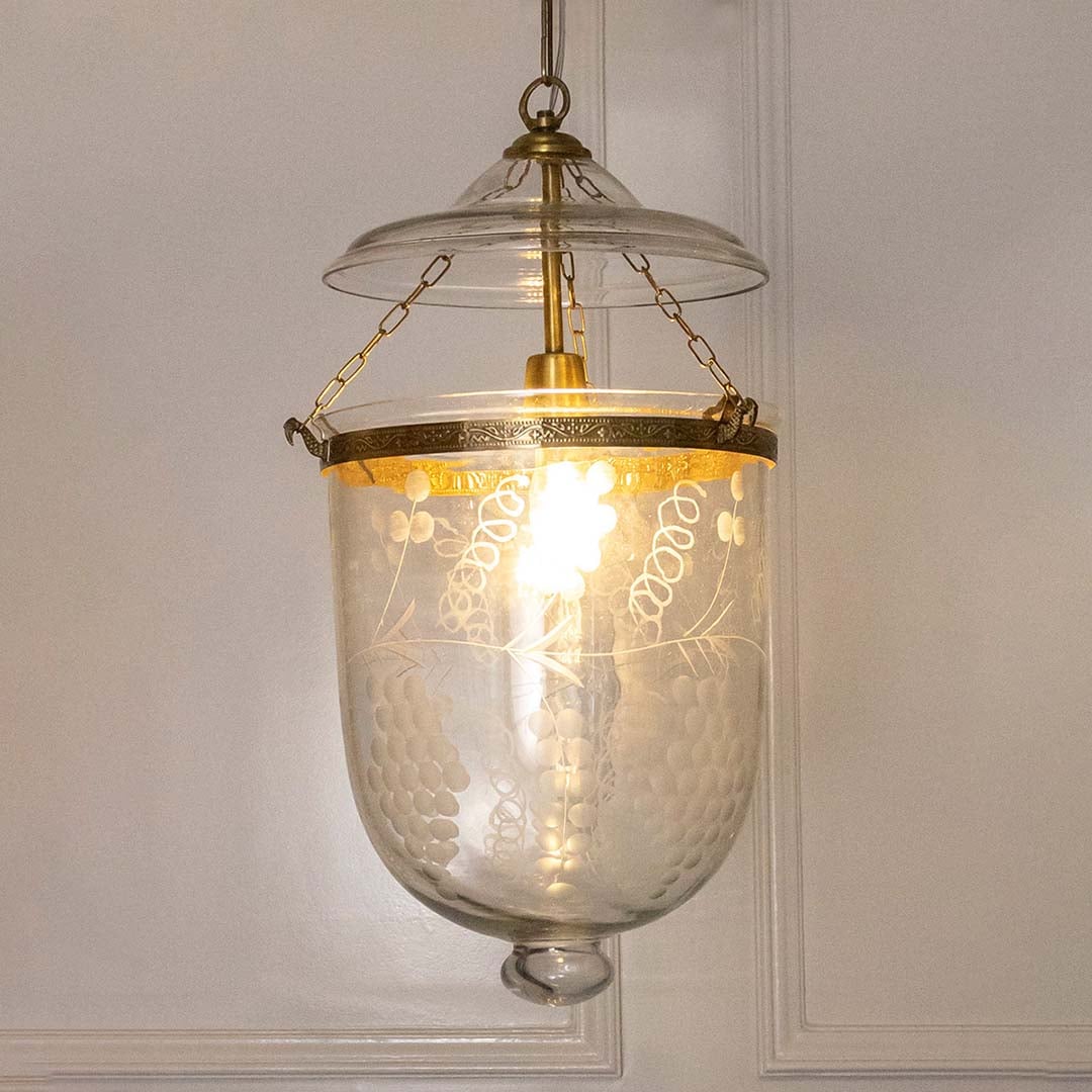 Pendant light with antique metal frame and clear textured glass shade casting warm ambient illumination for dining spaces.
