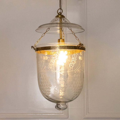 Pendant light with antique metal frame and clear textured glass shade casting warm ambient illumination for dining spaces.