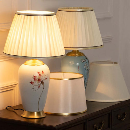 A set of two elegant table lamps with varying designs including a floral design and simple fabric shades  placed on a wooden dresser.