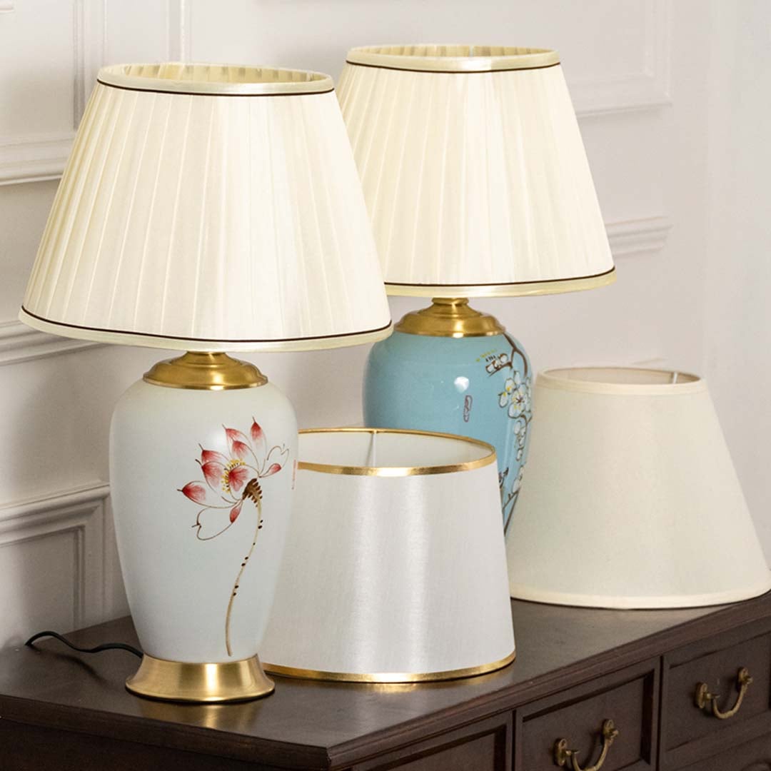 Elegant table lamps with pleated cream shades featuring hand-painted lotus and floral designs on wood furniture for home decor.
