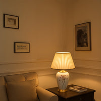 Elegant floral ceramic table lamp with gold metal base and cream pleated shade adds artistic charm and timeless sophistication to any home decor.