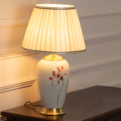 Floral ceramic table lamp with pleated fabric shade offering warm traditional lighting and elegant home decor appeal.
