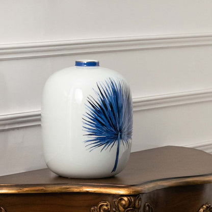 White ceramic jar with blue leaf artwork displayed in a closeup view showing delicate brushwork natural inspiration and minimalist décor aesthetics ideal for serene modern homes.