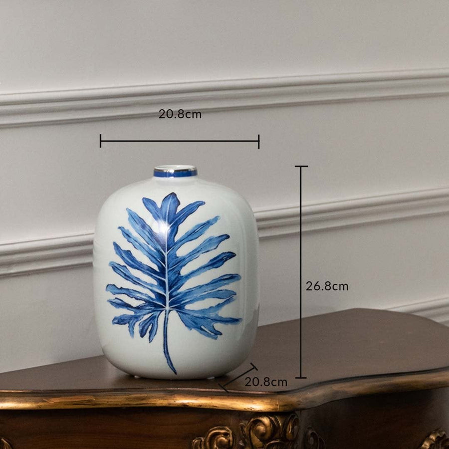 White ceramic jar with blue leaf artwork in a front view measuring 16 cm width and 20.5 cm height perfect for modern décor styling.
