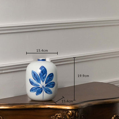 White ceramic jar with blue flower artwork in a front view measuring 16 cm width and 20.5 cm height ideal for clean minimalist décor styling.