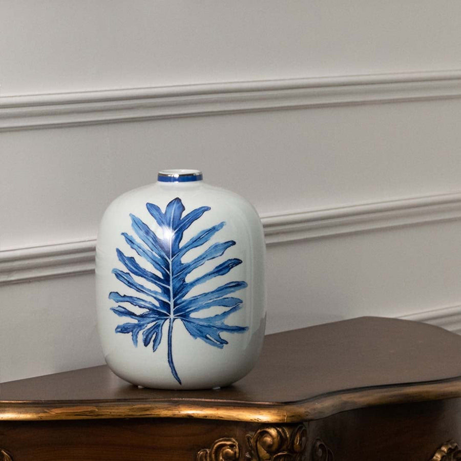 White ceramic jar with blue leaf artwork in a front view ideal for modern décor styling and elegant tabletop placement.