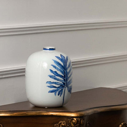 White ceramic jar with blue leaf artwork in a front view perfect for modern décor styling and elegant home accents.