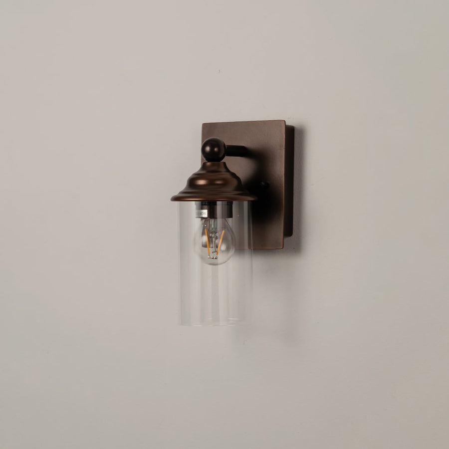 Stylish bronze wall sconce with clear glass shade shown off on a clean white background for product clarity.