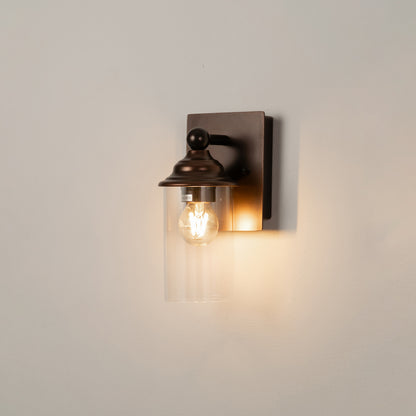 Black metal wall light on white background with exposed bulb and warm glow for industrial wall decor.