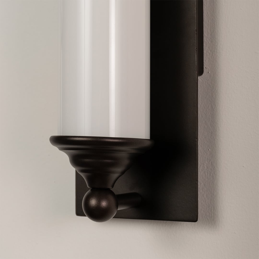 Close detail of black metal wall light with frosted glass tube showcasing premium finish for modern decor.