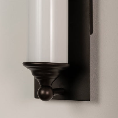 Close detail of black metal wall light with frosted glass tube showcasing premium finish for modern decor.