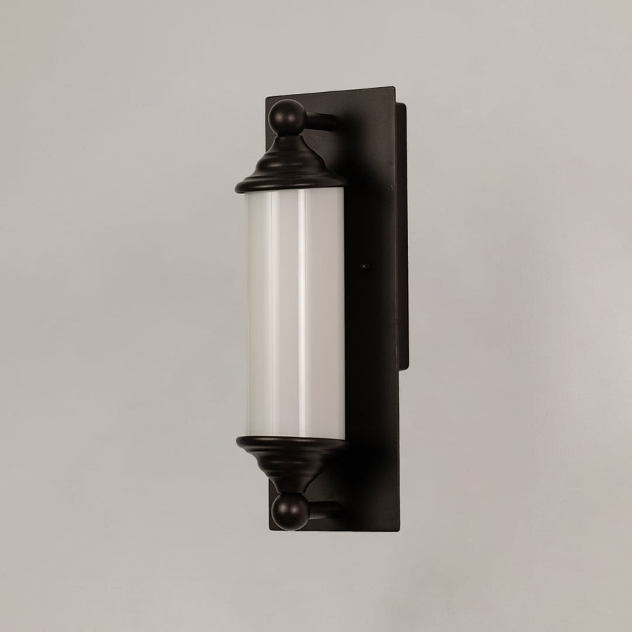 Black metal wall sconce with frosted glass tube shown on white background ideal for hallways and entry decor.