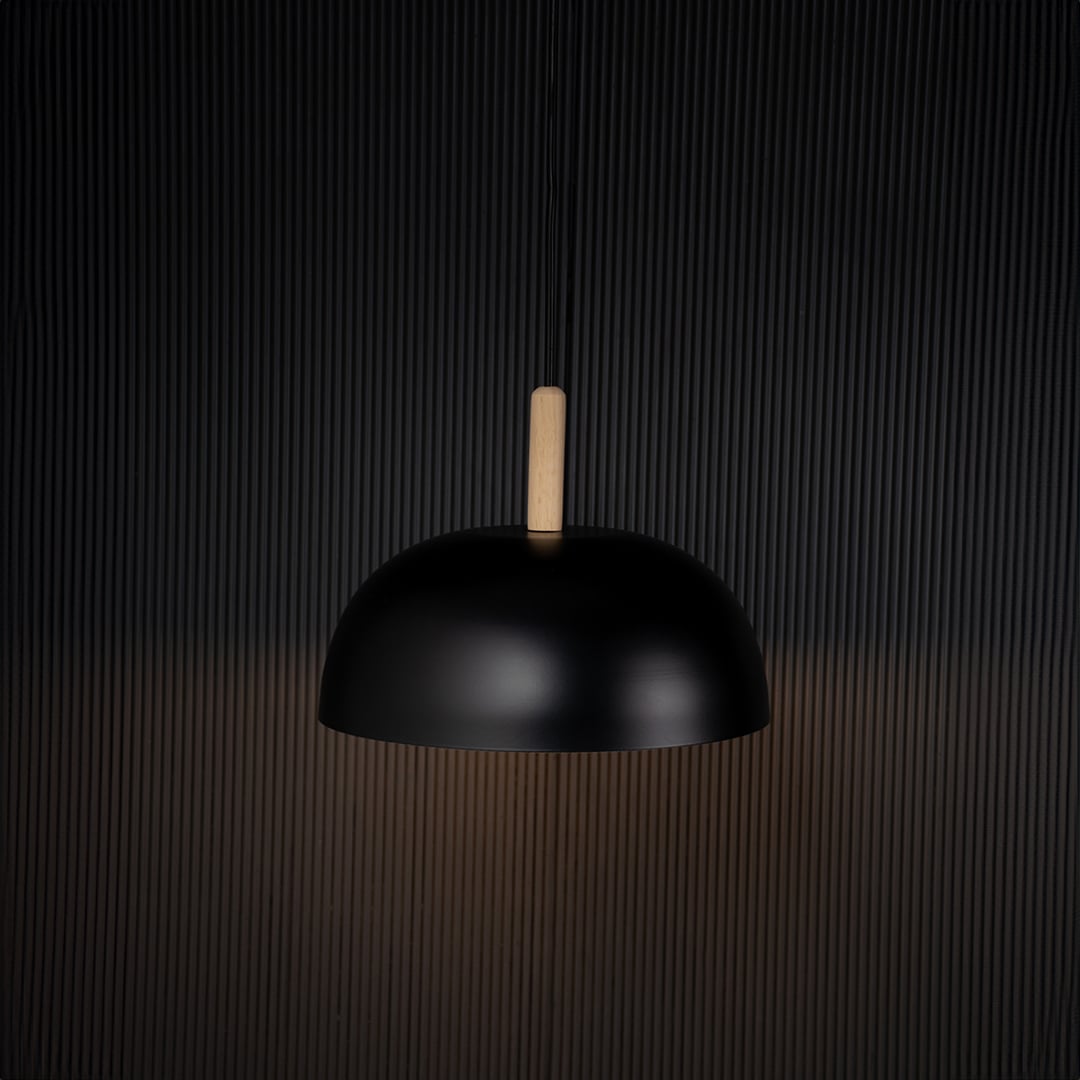 Black dome pendant ceiling light with wooden top illuminated on back background for dining room cafe and modern home interior lighting.